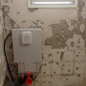 קיר חשוף עם צנרת ושקע חשמל במהלך שיפוץ