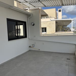 גג עם פרגולה מתכתית ומעקה זכוכית