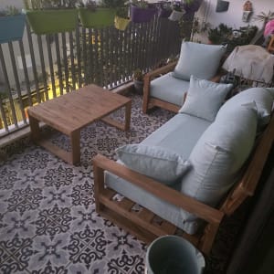 מרפסת עם עציצים, כורסאות ושולחן עץ.