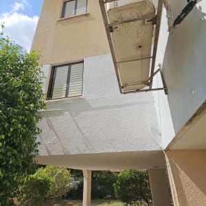 פיגום תלוי ליד בניין עם חלונות ועצים