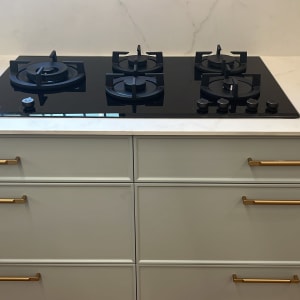 כיריים גז שחורות עם ארבעה מבערים על משטח שיש לבן