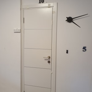 דלת לבנה עם ידית מתכת ומספרים על הקיר