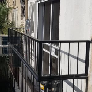 מעקה מתכת שחור על מרפסת עם דלת זכוכית