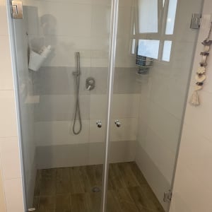 מקלחון זכוכית עם ראש מקלחת ומדף מוצרים