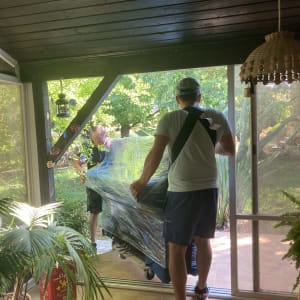 שני אנשים מזיזים רהיט עטוף בניילון נצמד