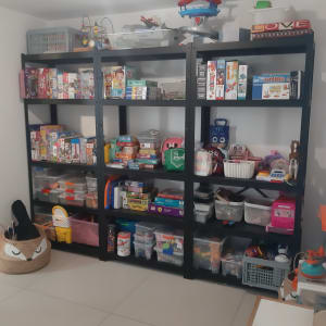 מדפים שחורים עם צעצועים ומשחקים מאורגנים בקופסאות