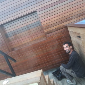 אדם צובע קיר עץ בגינה עם מברשת