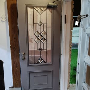 דלת אפורה עם חלון זכוכית מעוצב ומנגנון סגירה אוטומטי