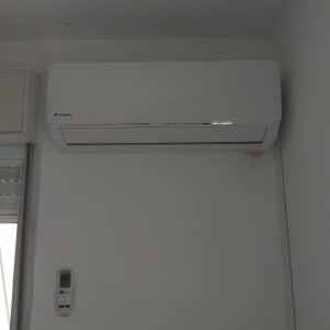 מזגן קיר לבן עם שלט רחוק על הקיר