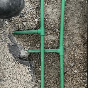 צינורות ירוקים מונחים על חצץ בעבודת אינסטלציה