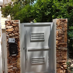 שער מתכת אפור בין עמודי אבן