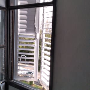 חלון אלומיניום פתוח עם תריסים לבנים