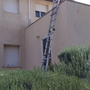 סולם מתכת נשען על קיר בית