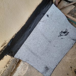 יריעה ביטומנית מונחת על רצפה ליד קיר