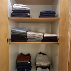 בגדים מקופלים ומסודרים בארון עץ פתוח