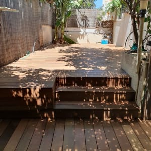 דק עץ בגינה עם מדרגות ועצים מסביב