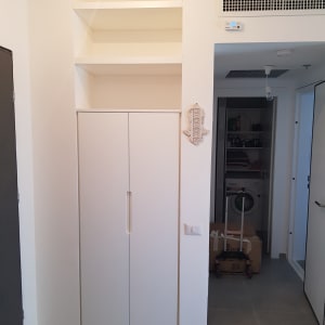 ארון לבן עם דלתות סגורות ומדפים מעליו