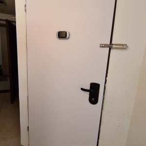 דלת לבנה עם עינית ומנעול שחור