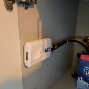 מכשיר גז לבן מותקן על קיר עם צינור מחובר