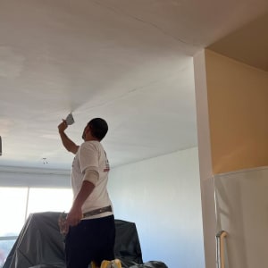 אדם צובע תקרה בעזרת מברשת על סולם