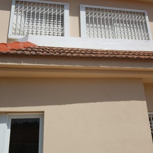 רעפים חומים על גג בית עם קיר לבן