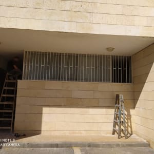 אדם על סולם מתקין סורגים על חלון