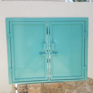 חלון מתכת תכלת עם מסגרת על קיר לבן