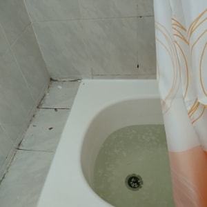 אמבטיה עם מים, וילון לבן עם דוגמאות כתומות