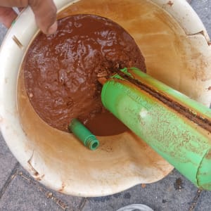 דלי עם מים חומים וצינור ירוק של דוד שמש