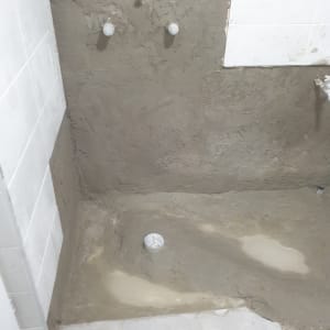 קיר ורצפה עם טיח טרי ושני ברזים