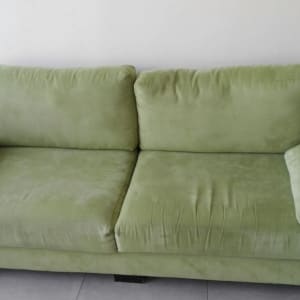 ספה ירוקה עם כריות על משטח חלק