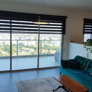 וילונות גלילה שחורים על חלונות גדולים בסלון