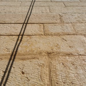 קיר אבן עם צל של כבלים אנכיים