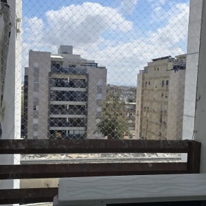 רשת יונים מותקנת על מרפסת עם נוף לבניינים