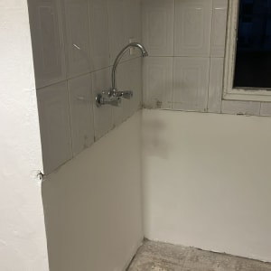 כיור עם ברז על רקע קיר לבן ורצפת אריחים ישנה