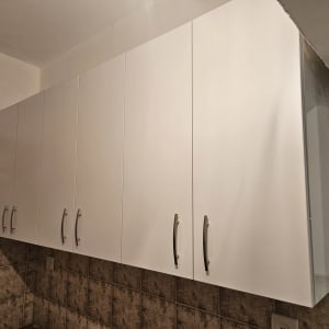 ארונות מטבח לבנים עם ידיות מתכת על קיר מרוצף