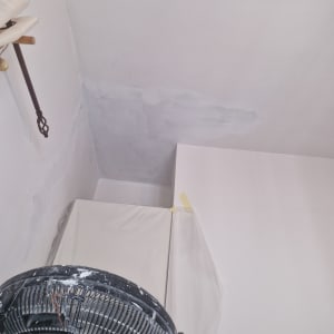 קיר צבוע חלקית עם מאוורר וצבע לבן