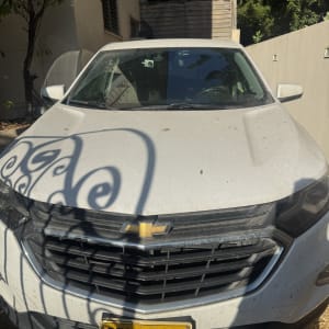 רכב לבן עם לוחית רישוי צהובה בחניה