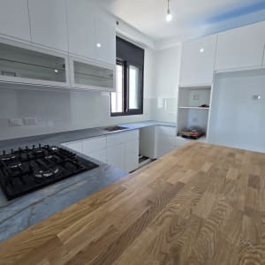 מטבח חדש עם ארונות לבנים ומשטח עץ