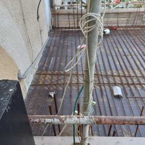 רשת ברזל על רצפת בטון בבנייה, כבלים חשמליים תלויים.