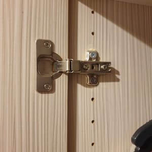 ציר מתכת מותקן על דלת עץ בארון