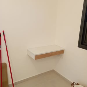 מדף עץ תלוי עם מגירות על קיר לבן