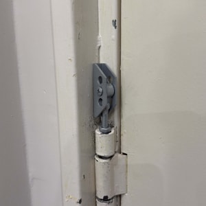 ציר דלת מתכת מותקן על משקוף לבן