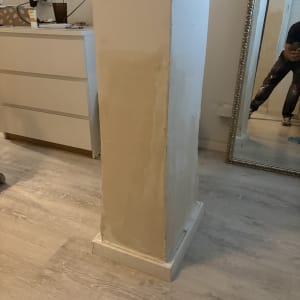 תיקון טיח ושפכטל על עמוד קיר במהלך עבודת שיפוץ בבית