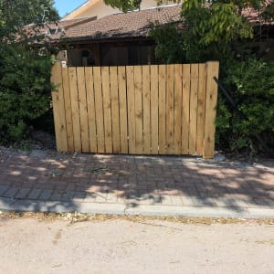 גדר עץ חדשה בין שיחים ירוקים