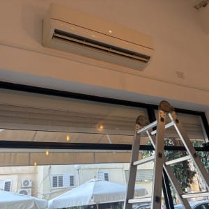 מזגן מותקן על קיר עם סולם מתחתיו