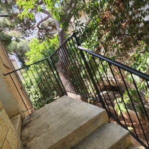 מעקה מתכת שחור על מדרגות אבן חיצוניות