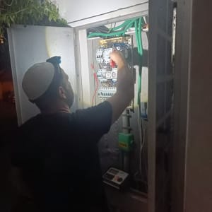 חשמלאי עובד על לוח חשמל עם פנס ראש