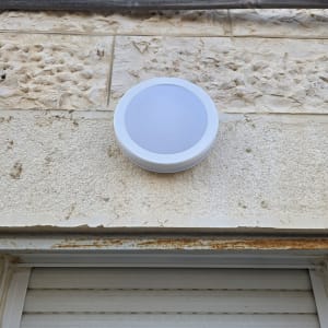 גוף תאורה עגול שהותקן על קיר אבן חיצוני