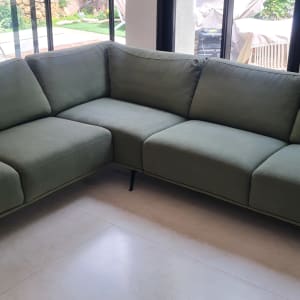 ספה ירוקה בחדר מגורים עם שולחן וכיסאות